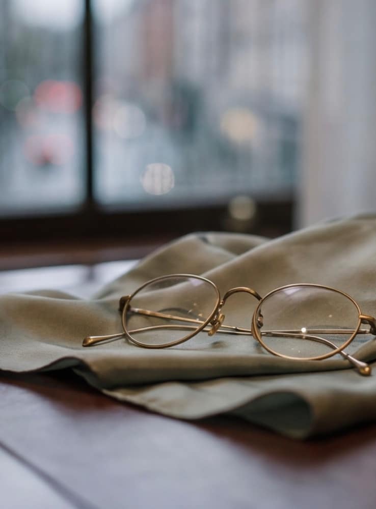 Reading glasses resting on folded linen beside a window